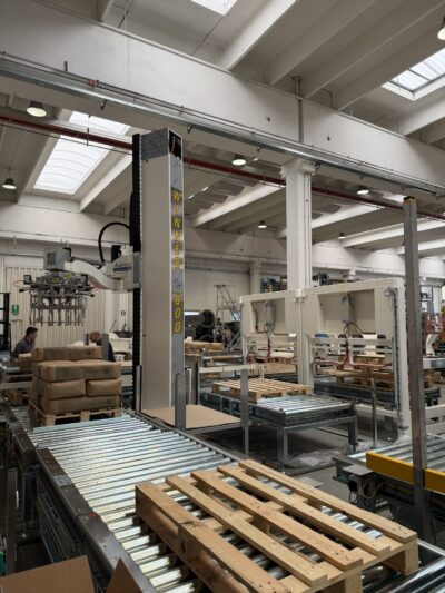 Een lege pallet wordt over de rollenbanen vervoerd tot bij de robotpalletiser die de zakken correct stapelt