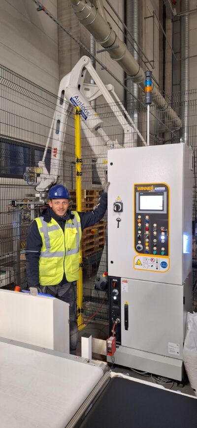 Jonas, een technieker van Ausloos staat langs een machine die geïnstalleerd werd door Ausloos