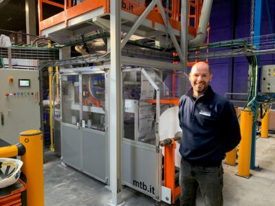 Een collega van Ausloos poseert bij een verpakkingsmachine bij de oplevering ervan